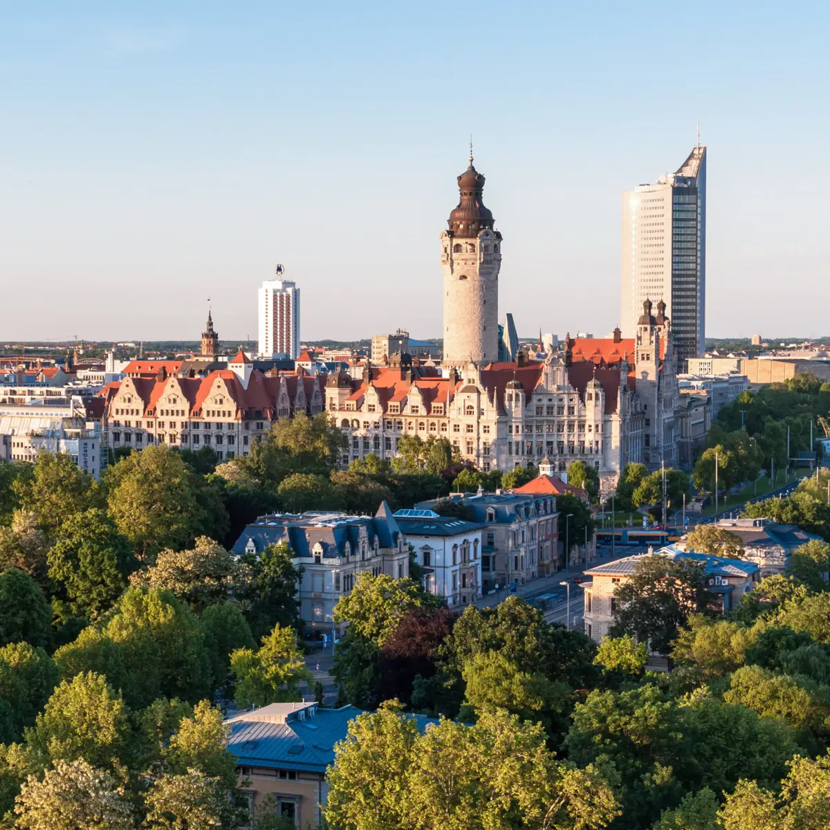 De skyline van Leipzig met bomen en gebouwen in het ochtendlicht.