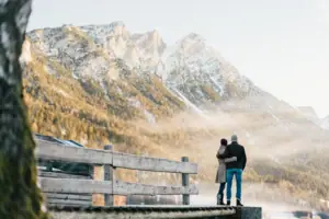 Een man en een vrouw staan op een steiger met uitzicht op een bergketen.
