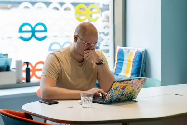 Een man zit aan een tafel en ondersteunt zijn gezicht met zijn hand.