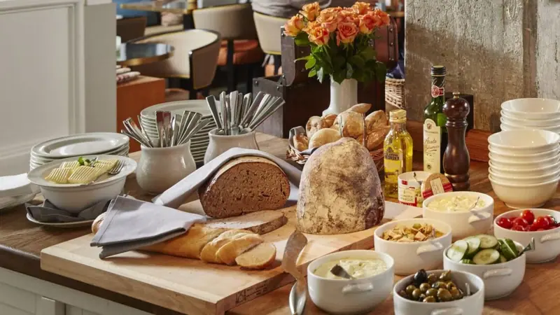 Diner bij HENRI Er staat een snijplank met brood en een paar kleine schaaltjes eten op een tafel.