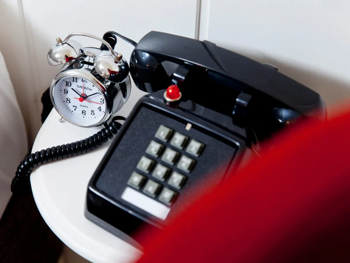 Retro telefoon en zilveren wekker op een wit bijzettafeltje