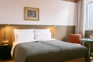 Kamer en bed Een bed met kussens en een lamp in een kamer.