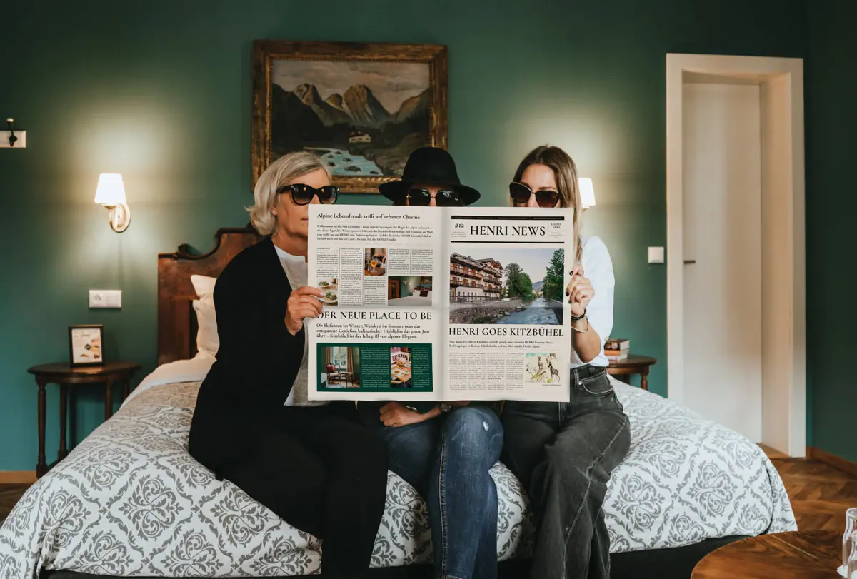 Een groep mensen zit op een bed een krant te lezen.