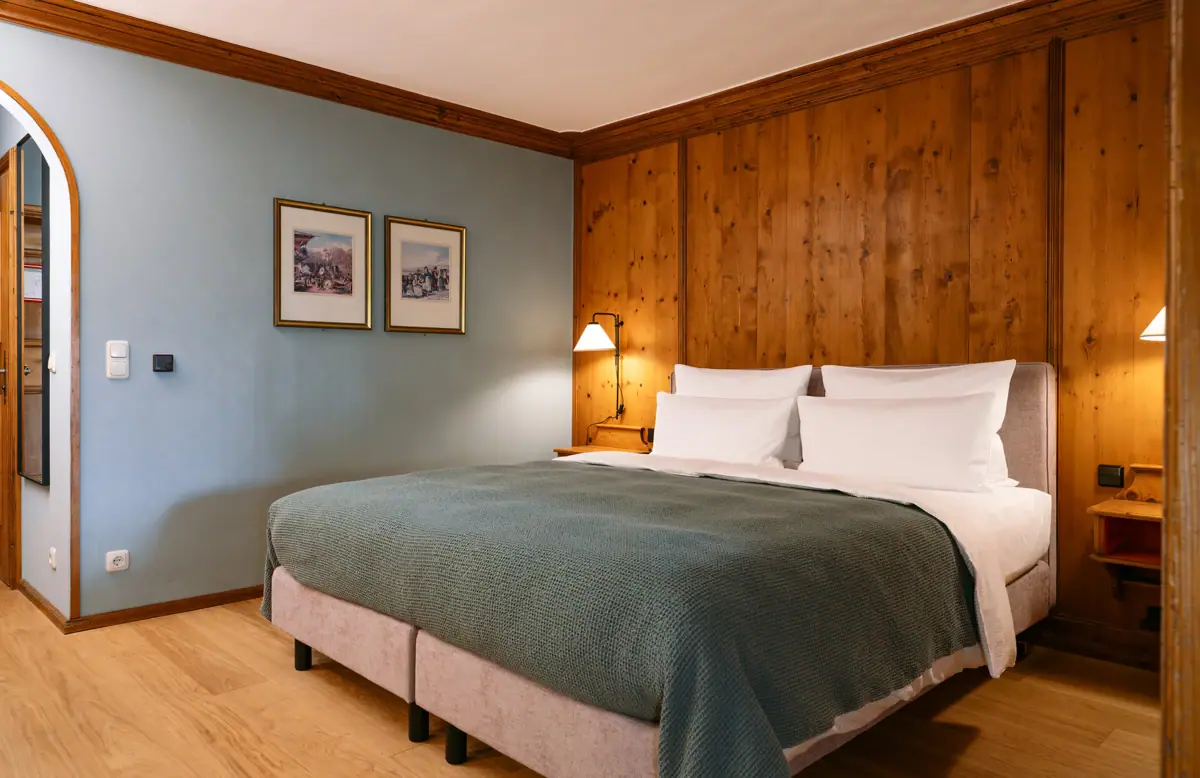 Een bed met een houten lambrisering en een lamp.