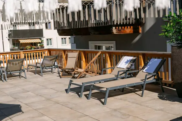 Een terras met stoelen en een witte parasol.