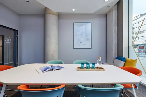 Bijenkorf Düsseldorf Een tafel met blauwe stoelen en een boek erop.