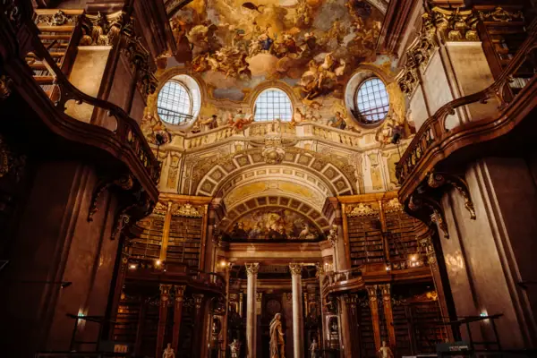Een grote, sierlijke bibliotheek met een plafondfresco.