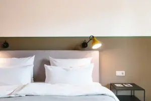 Een bed met witte kussens voor een tweekleurige muur in het HENRI Hotel Garmisch-Partenkirchen.