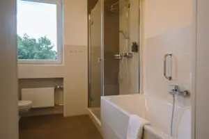 HENRI GAP-salon met balkon Badkamer met douche en bad, voorzien van moderne kranen en een spiegel.