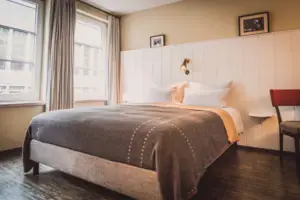 Bed met lamp en raam in een stijlvolle hotelkamer.