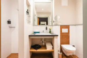 Badkamer Badkamer met wastafel en toilet, uitgerust met spiegel en fittingen.