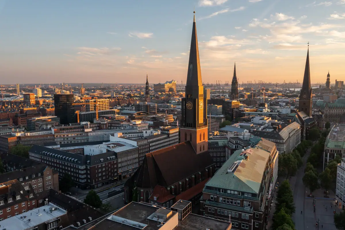 Stadsgezicht met hoge kerktoren en licht bewolkte lucht.