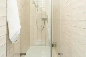 Badkamer HENRI Kitzbühel Douche met glazen deur en tegels.