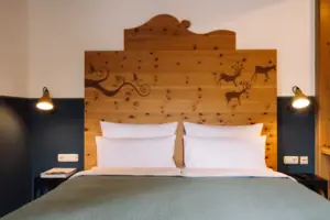 HENRI GAP-salon met balkon Bed met houten hoofdeinde en wit beddengoed in een hotelkamer