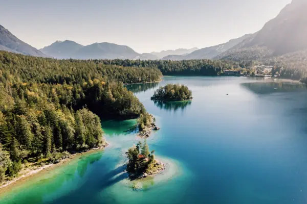 Meer met helderblauw water en groene dennenbomen 
