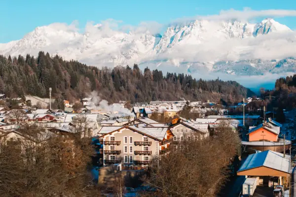 HENRI Kitzbühel drone uitzicht Een bergdorpje met besneeuwde bergen op de achtergrond.