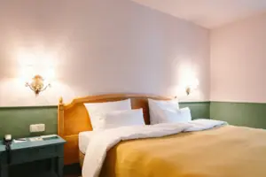 De hotelkamer Chambre met balkon in het HENRI Hotel Garmisch-Partenkirchen met een bed voor een groen-witte muur.