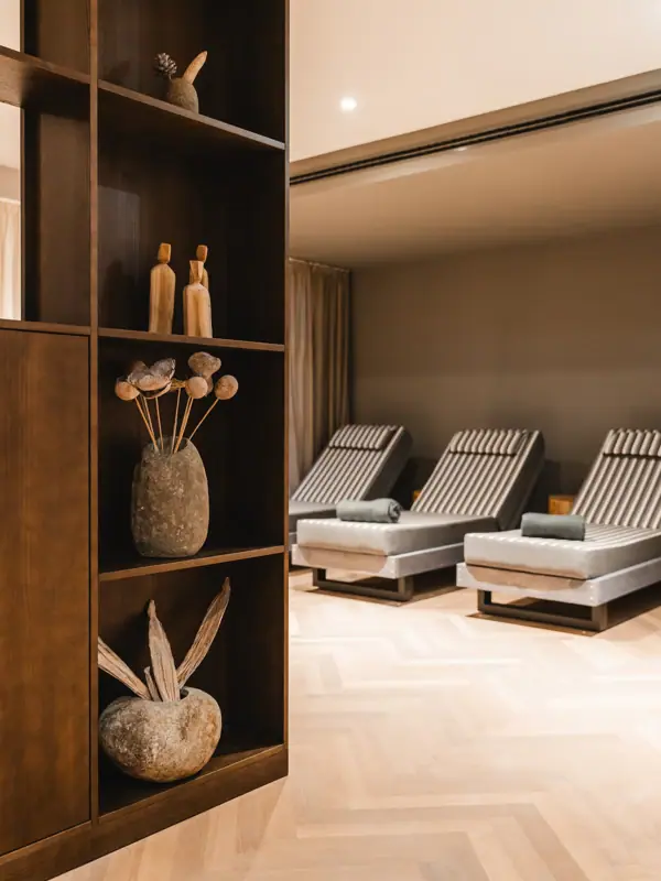 Een kamer met stoelen en een plank met vazen en bloemen.