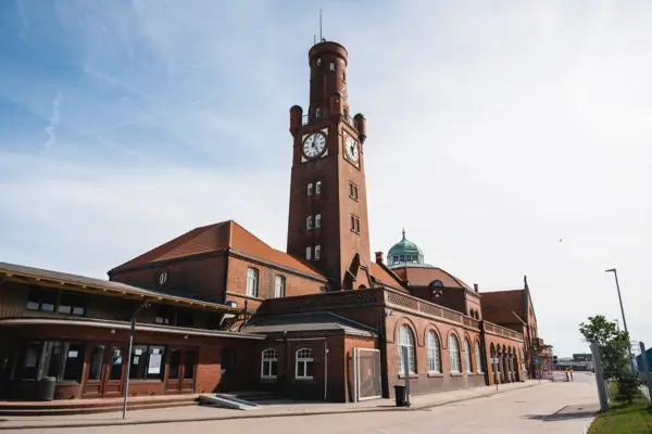 De Hapag-Hallen in Cuxhaven: een bakstenen gebouw met een klokkentoren onder een bewolkte hemel.